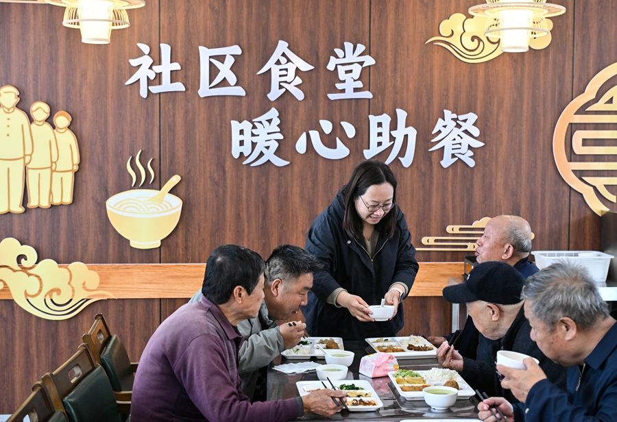 在江苏省扬州市江都区邵伯镇甘棠社区幸福邻里食堂，社区工作人员（左三）给老年居民端汤（2026年4月29日摄）。